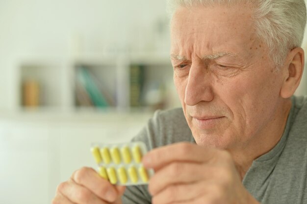 Homme malade âgé avec des pilules à la main