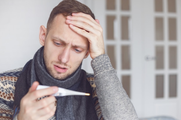 Un homme malade apprend sa température élevée à la maison dans le salon.