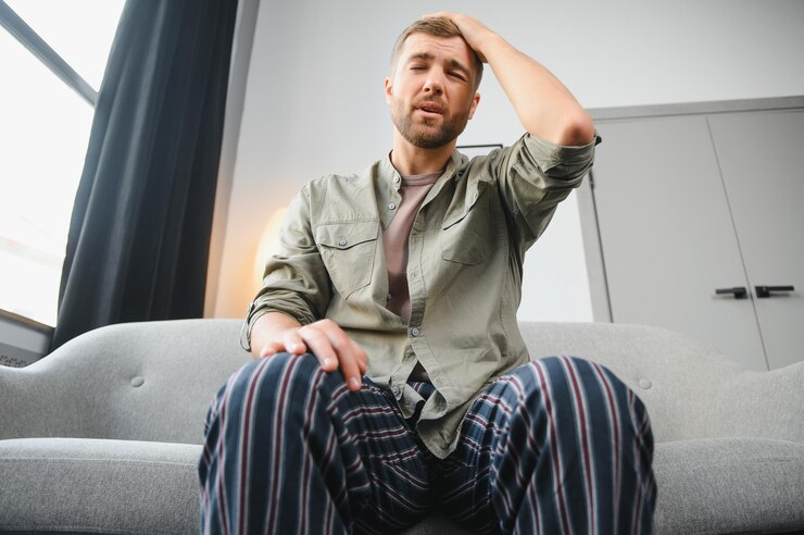Photo homme malade assis sur son lit avec sa tête sur sa main