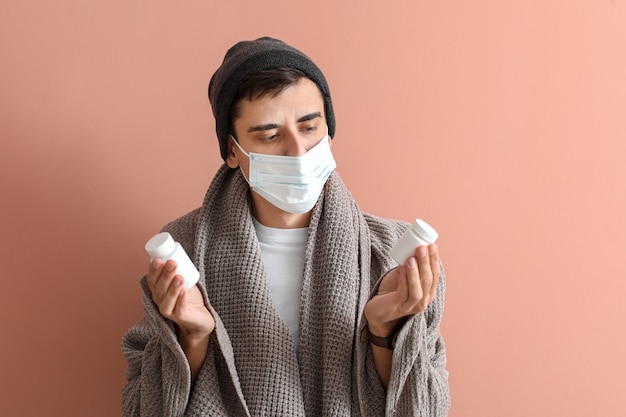 Homme malade avec des pilules sur la surface de couleur