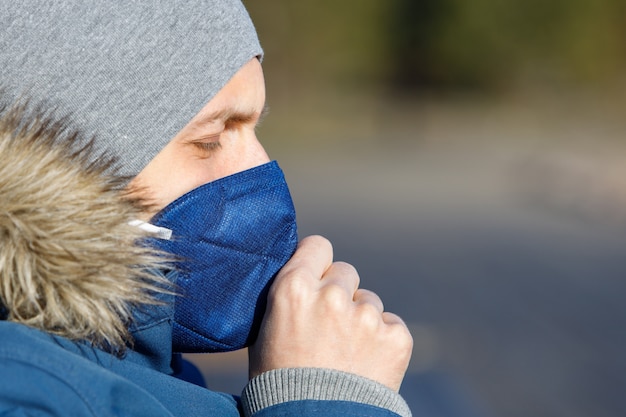 Photo homme malade en veste bleue avec un capuchon ayant un rhume, la toux et portant un masque médical