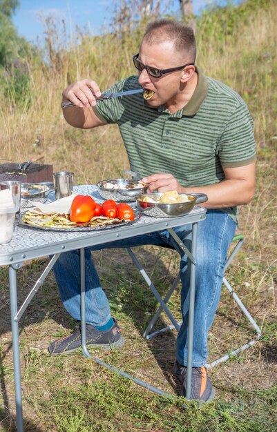 Un homme mange un repas dans un champ