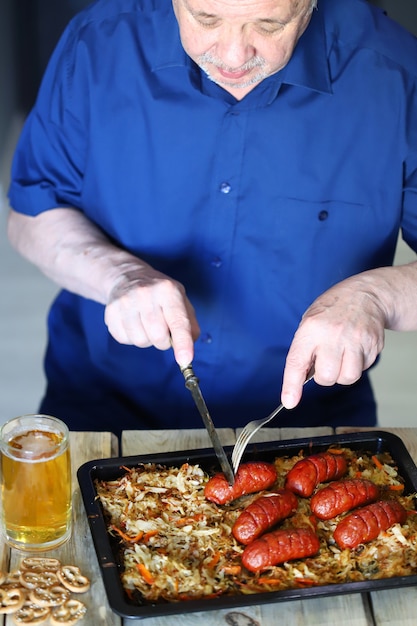 Un homme mange des saucisses avec de la choucroute et de la bière.