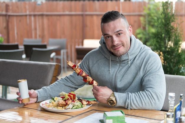 Homme mangeant du poulet avec du riz dans un restaurant en plein air