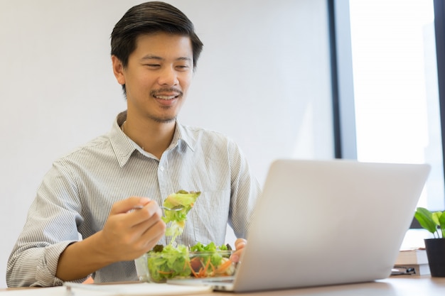 homme mangeant des légumes biologiques et un bol de salade propre