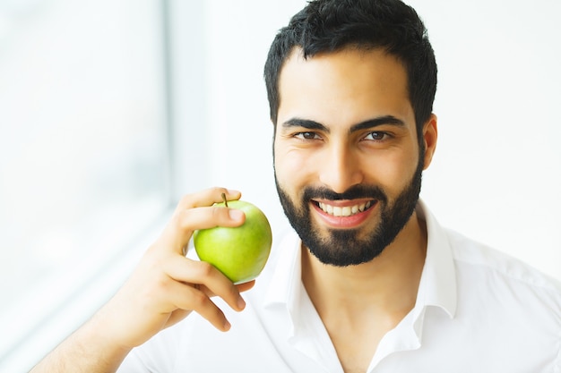 Homme mangeant la pomme. Belle fille aux dents blanches mordant la pomme. Image haute résolution