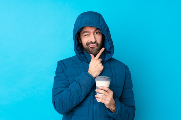 Homme avec manteau d'hiver sur mur bleu isolé