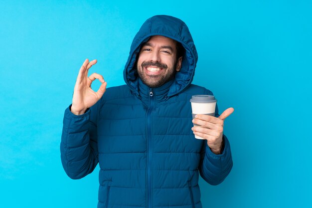 Homme avec manteau d'hiver sur mur bleu isolé