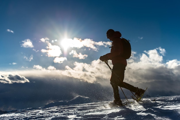 Homme marchant dans la neige avec des raquettes