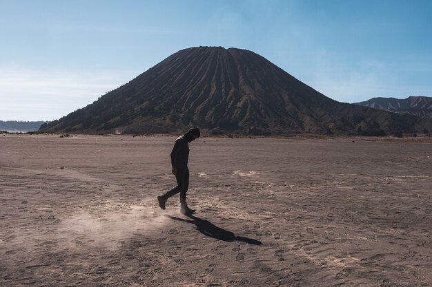 Homme marchant sur le désert avec des poussières à près d'un volcan Batok dans le parc national Bromo Tengger Semeru