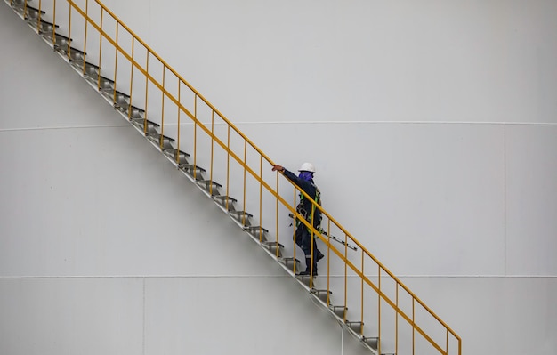 Un homme marchant à l'étage inspection visuelle enregistrement réservoir de stockage escaliers d'huile sur la plaque de coque latérale