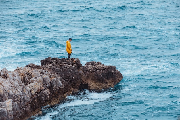 Homme marchant par rock à la mer déchaînée