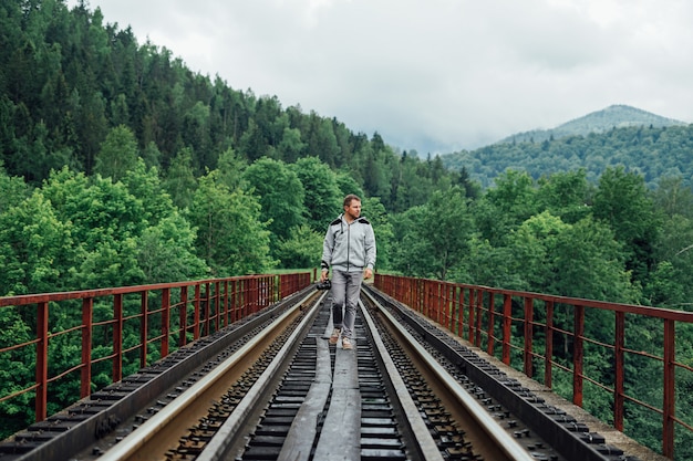 Homme marchant sur un pont de chemin de fer dans les bois