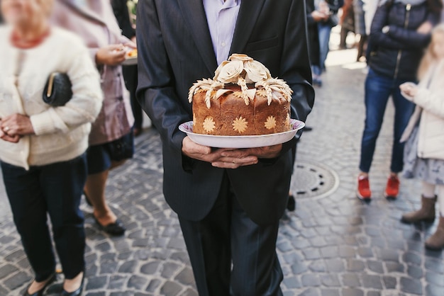 Homme marchant et tenant un gâteau de mariage ukrainien traditionnel avec des roses délicieux pain brun