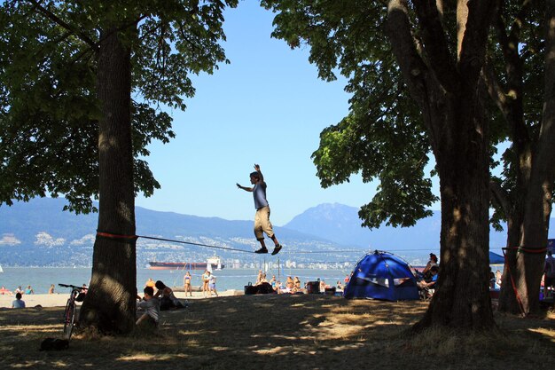 Photo un homme marche sur une corde sur la plage de jéricho à vancouver, au canada