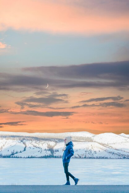 Photo un homme marche sur un lac gelé contre le ciel au coucher du soleil.