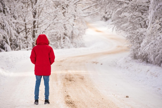 Un homme marche le long d'une route à travers une forêt enneigée. repos hivernal.