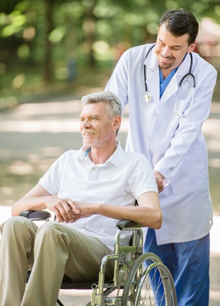 L'homme marche avec un patient âgé en fauteuil roulant.