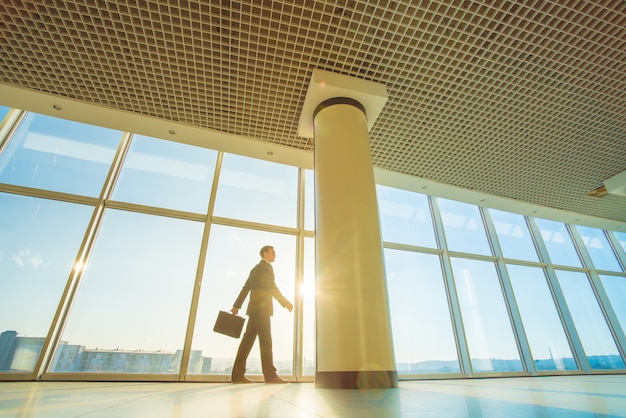 L'homme marche avec une valise sur fond de soleil