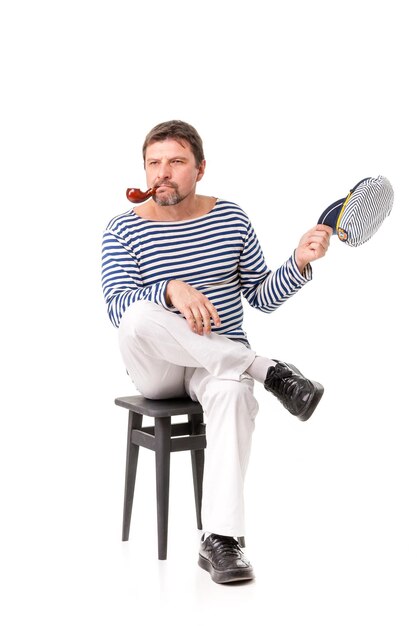 Un homme marin dans une casquette avec une pipe devant un fond blanc