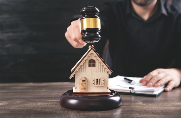 Homme avec marteau de juge et modèle de maison. Avocat Immobilier