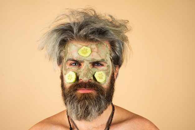 Homme avec masque d'argile et tranches de concombre sur le visage spa dermatologie bien-être et concept de traitement du visage...