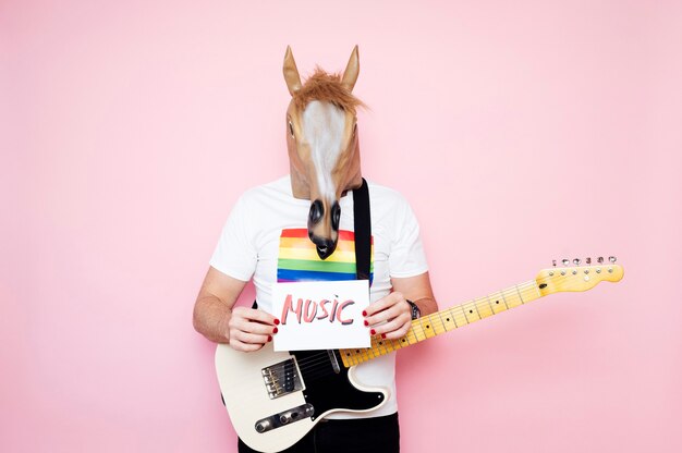 homme avec masque de cheval tient une affiche qui met de la musique