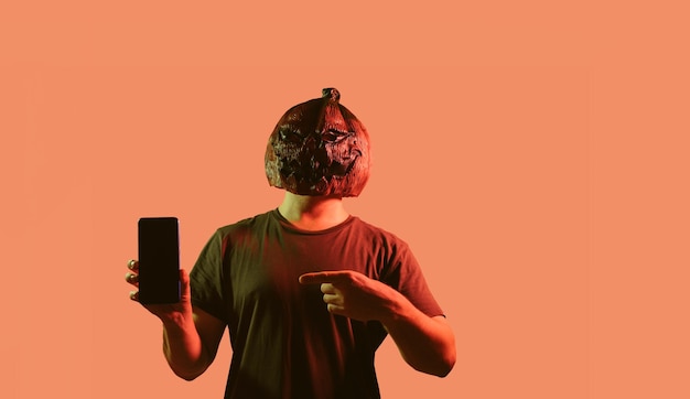 Un homme avec un masque de citrouille pointe vers un concept publicitaire pour smartphone