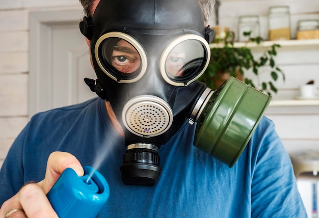 Photo un homme avec un masque à gaz désinfecte une pièce à la maison.