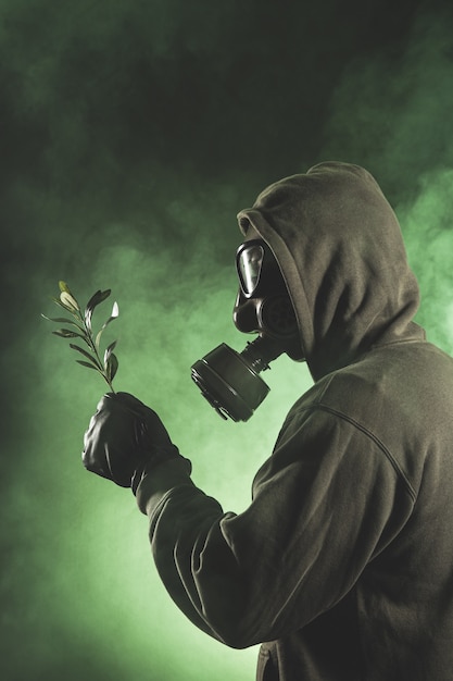 Photo homme avec masque à gaz tenant une branche avec des feuilles