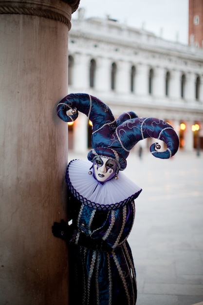 Homme Masqué En Personnage D'arlequin à La Mascarade Vénitienne Coup D'oeil Derrière Un Pilier, Sur La Rue De Venise