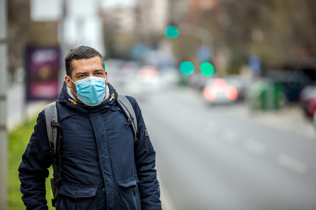 Photo homme avec un masque de protection sur son visage est debout dans la rue