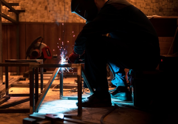 Homme avec masque de soudage métal dans l'atelier