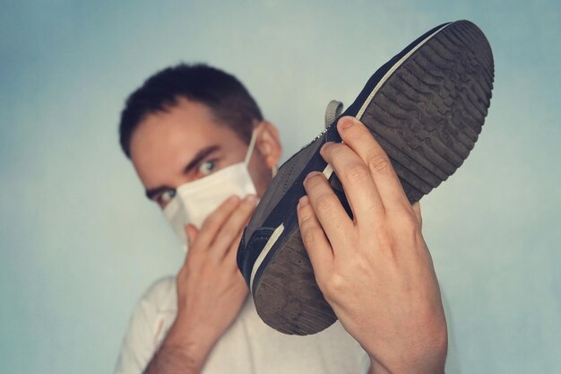 Un homme avec un masque tient un concept d'odeur désagréable de chaussure puante sale