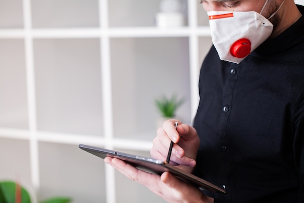 Homme masqué travaillant sur tablette au bureau de l'entreprise