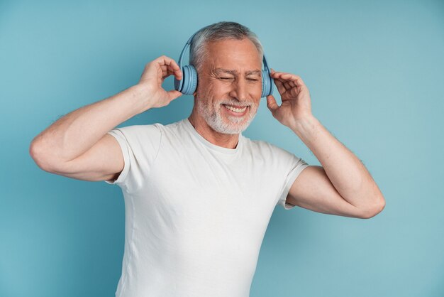 Homme mature aux cheveux gris avec un casque d'écoute de la musique.