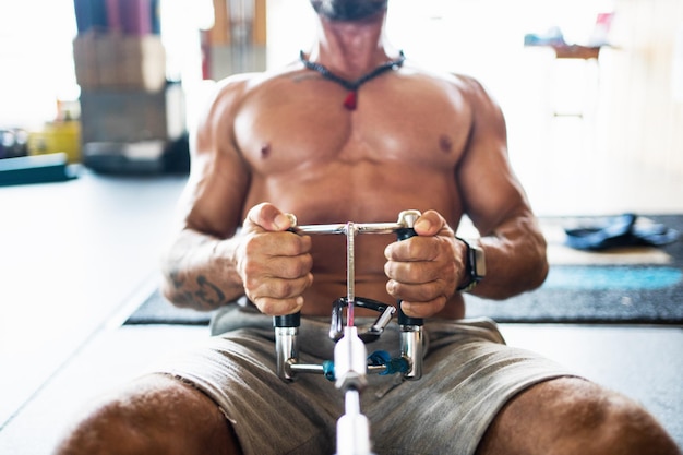 Homme méconnaissable faisant des exercices de traction sur une machine de gym