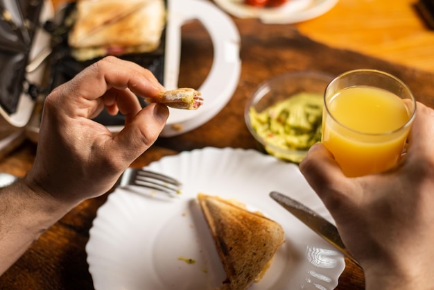 Un homme méconnaissable mange du pain grillé sur une assiette L'heure du petit-déjeuner Les mains de l'homme tiennent un couteau et une fourchette
