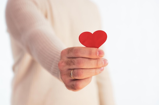 Homme méconnaissable tenant un petit coeur rouge dans sa main