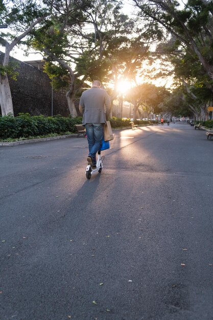 Homme méconnaissable transportant des achats sur un scooter électrique