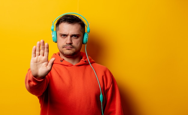 Homme mécontent avec des écouteurs sur le mur jaune