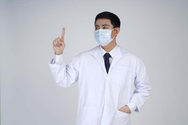 Homme médecin asiatique en masque médical, doigt pointé