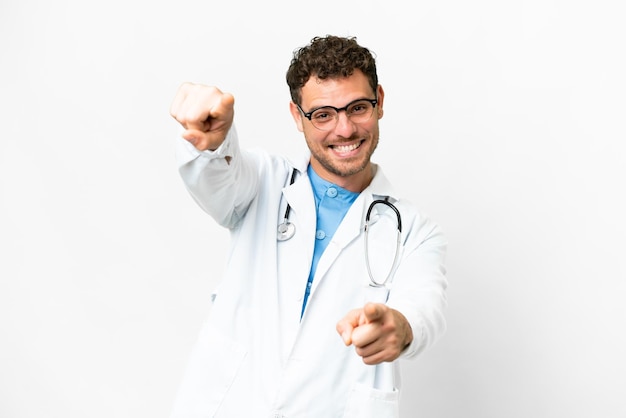 Homme médecin brésilien sur fond blanc isolé pointe le doigt vers vous en souriant