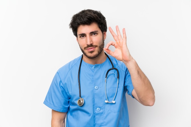 Homme médecin chirurgien sur mur blanc isolé, montrant un signe ok avec les doigts