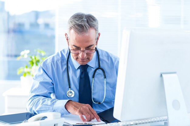 Homme médecin examinant le document à l&#39;hôpital