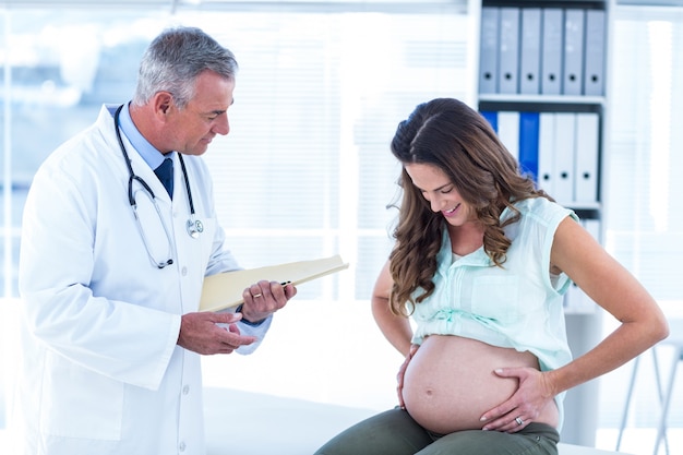 Homme médecin examinant une femme enceinte en clinique