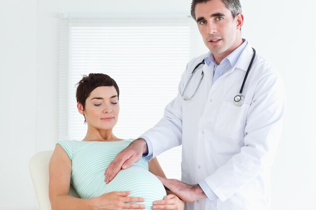 Homme Médecin Examinant Le Ventre D'une Femme Enceinte