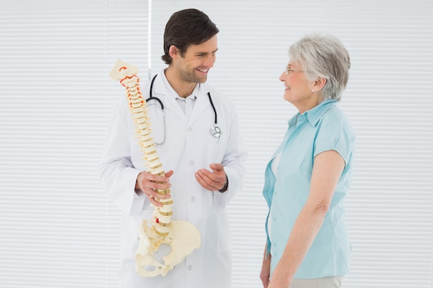 Homme médecin expliquant la colonne vertébrale à un patient âgé