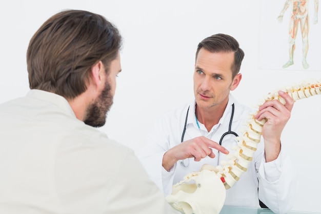 Homme médecin expliquant la colonne vertébrale à un patient
