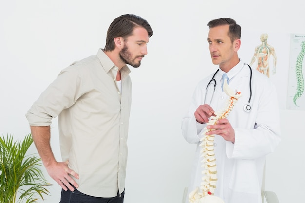 Homme médecin expliquant la colonne vertébrale à un patient